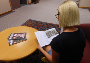 A woman sitting at a coffee table reading Outlook magazine