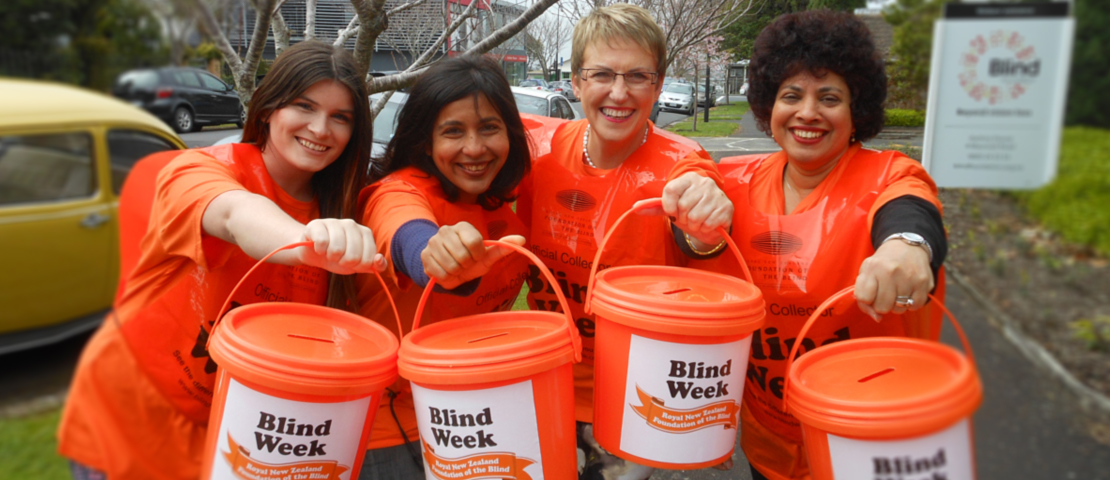 A group of Blind Week street collectors holding out orange buckets
