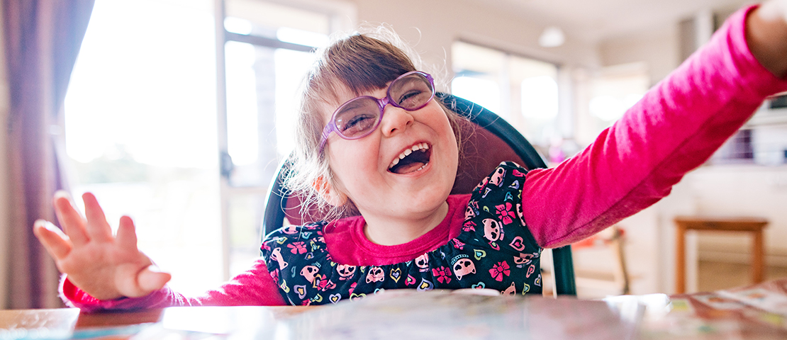 A young girl in purple glasses laughing