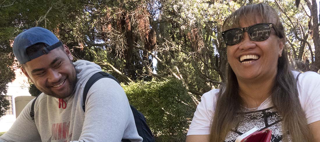 A young man and older woman laughing in the sunshine.